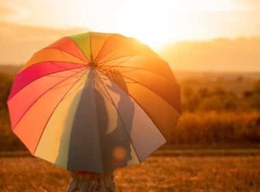 Jeune fille cachée sous un parapluie multicouleur