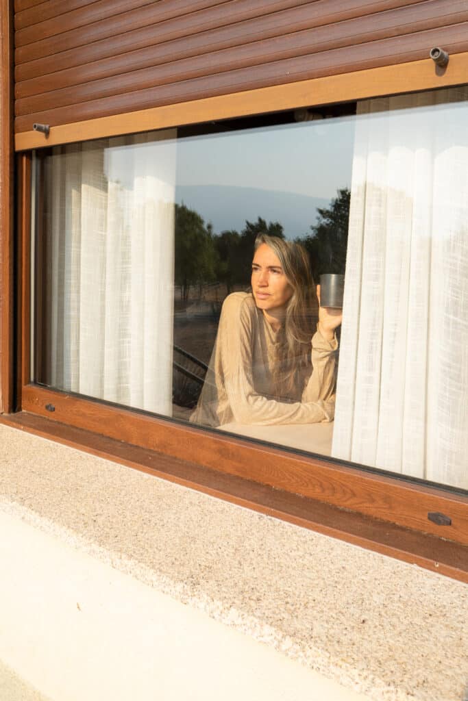 Femme buvant son café derrière sa fenêtre équipée de volet roulant