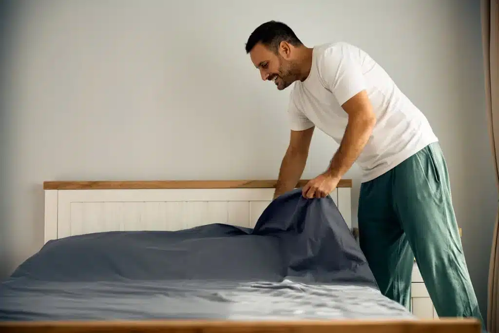 Homme faisant son lit le matin