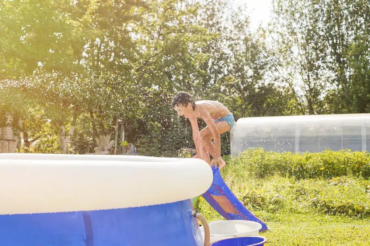 Jeune garçon sautant dans une piscine hors sol